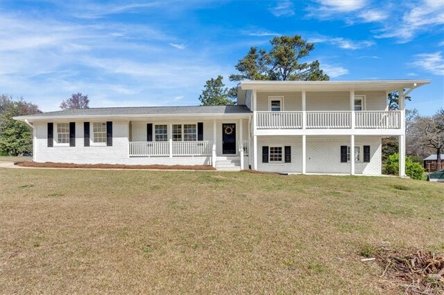 split level home with brick siding, covered porch, and a front yard