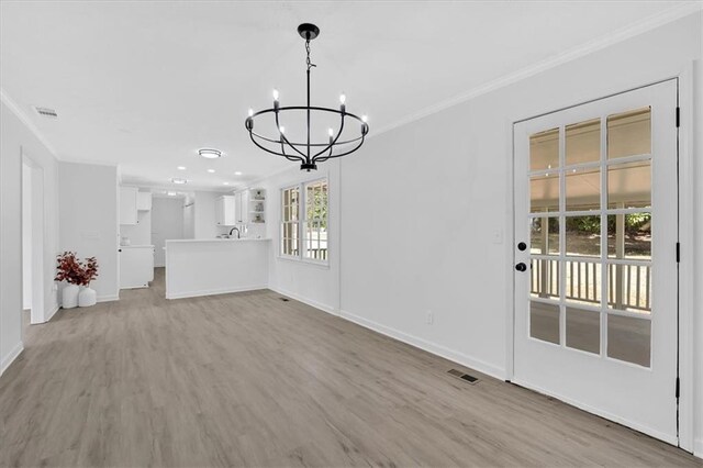 unfurnished dining area with a notable chandelier, baseboards, light wood-style floors, and ornamental molding