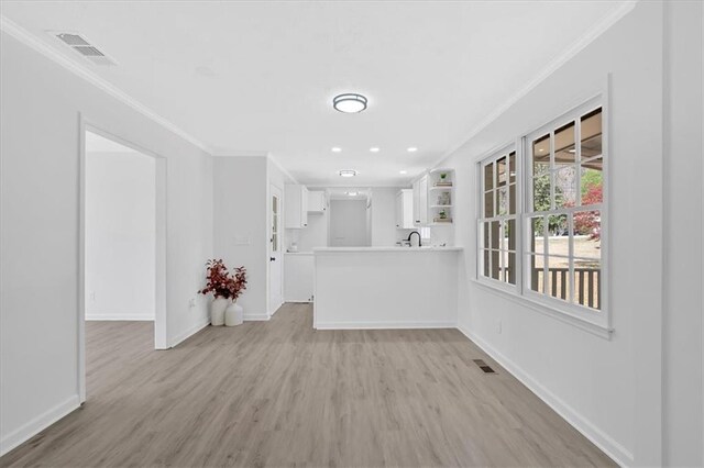 unfurnished living room featuring crown molding, baseboards, and light wood-type flooring