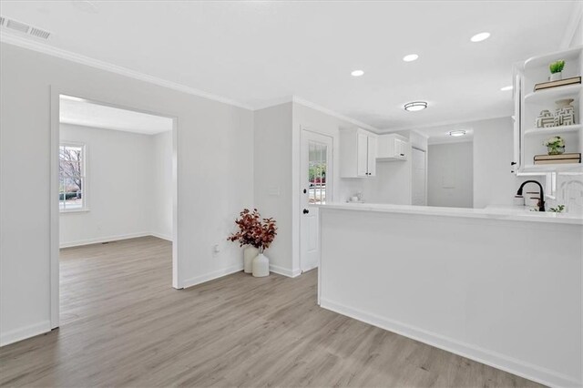 kitchen with ornamental molding, open shelves, light wood-style floors, white cabinets, and light countertops