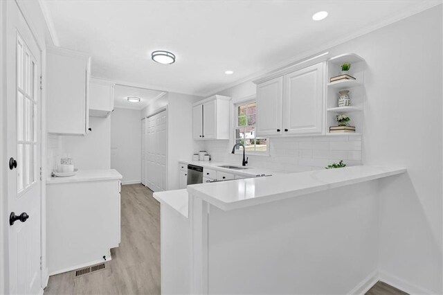 kitchen with open shelves, dishwasher, light countertops, decorative backsplash, and a sink