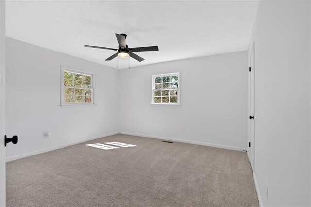 carpeted spare room featuring baseboards, a healthy amount of sunlight, and a ceiling fan