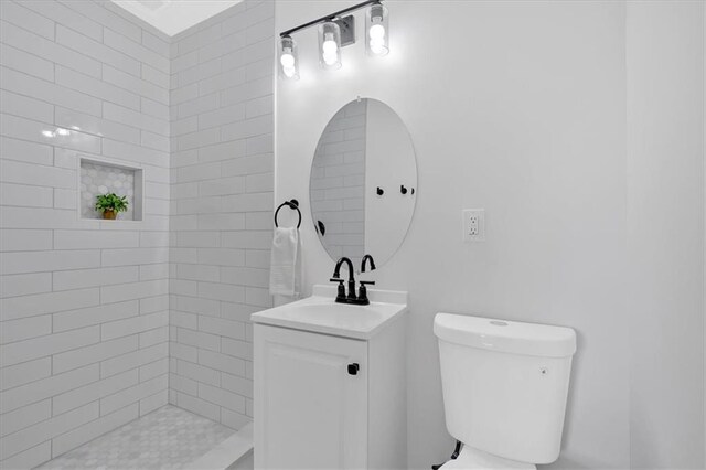 bathroom with toilet, vanity, and a tile shower