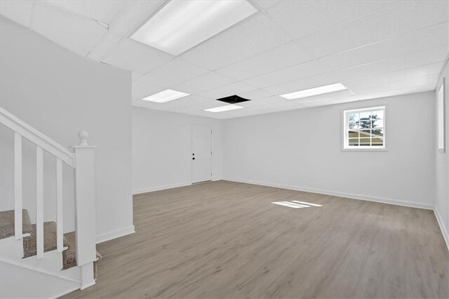 spare room with a drop ceiling, stairway, baseboards, and wood finished floors