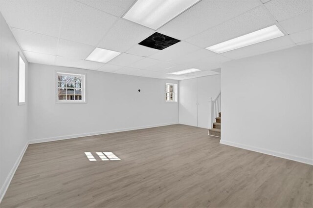 basement featuring stairway, a paneled ceiling, and wood finished floors