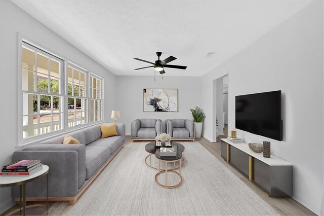 living room with visible vents, light wood-style flooring, and a ceiling fan