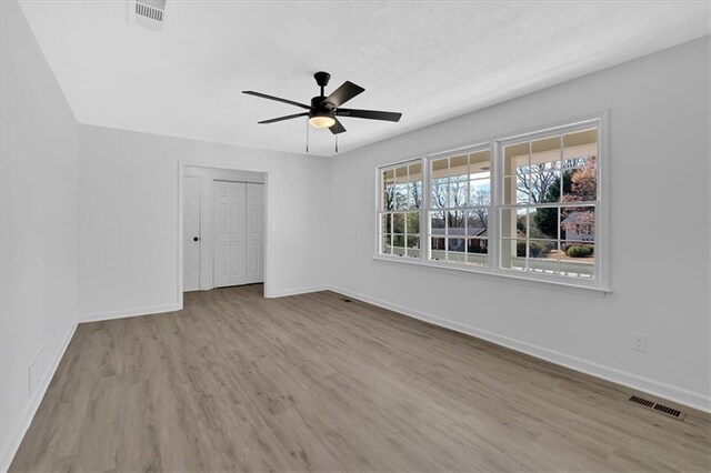 spare room featuring a ceiling fan, wood finished floors, visible vents, and baseboards