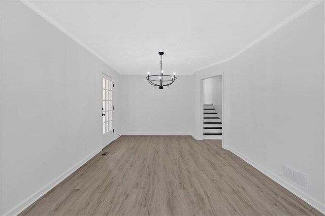unfurnished dining area featuring visible vents, an inviting chandelier, wood finished floors, and crown molding