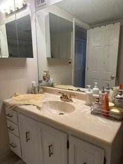 bathroom featuring vanity, visible vents, and a textured ceiling