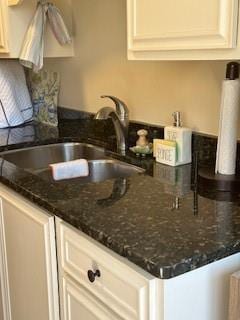 kitchen featuring dark stone countertops, a peninsula, and a sink