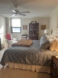 bedroom with a textured ceiling, crown molding, and ceiling fan