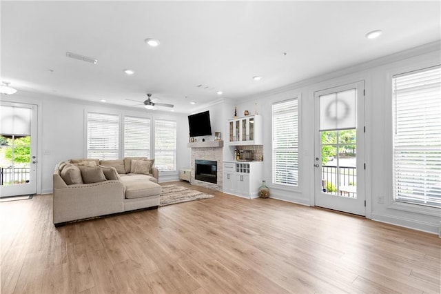 300 Olmstead Way, Alpharetta, GA 30022 - living room with crown molding, a glass covered fireplace, healthy amount of natural light, a ceiling fan, and light wood-style floors