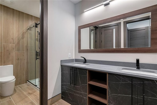 bathroom featuring double vanity, a sink, toilet, and a shower stall