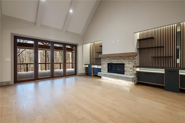 unfurnished living room with beamed ceiling, high vaulted ceiling, a fireplace, and wood finished floors