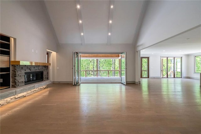 unfurnished living room with high vaulted ceiling, baseboards, a fireplace, and wood finished floors