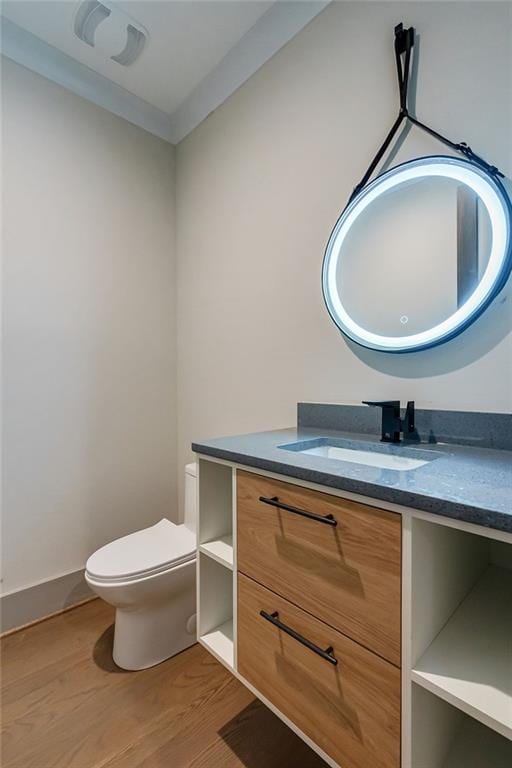 half bathroom with vanity, toilet, and wood finished floors