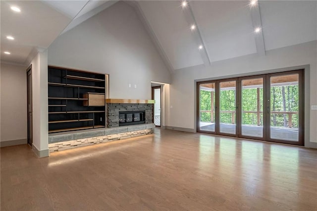 unfurnished living room featuring a stone fireplace, wood finished floors, baseboards, high vaulted ceiling, and recessed lighting