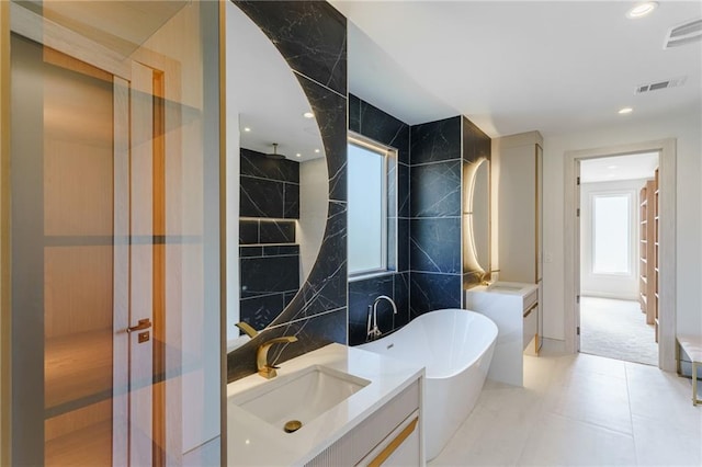 bathroom with a freestanding tub, visible vents, and vanity