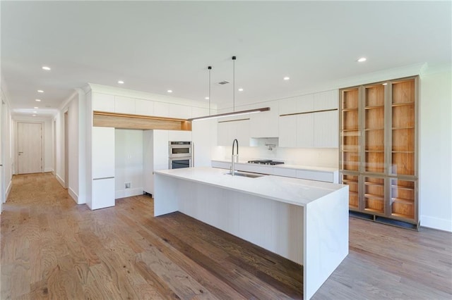 kitchen featuring a sink, light countertops, gas cooktop, and light wood finished floors