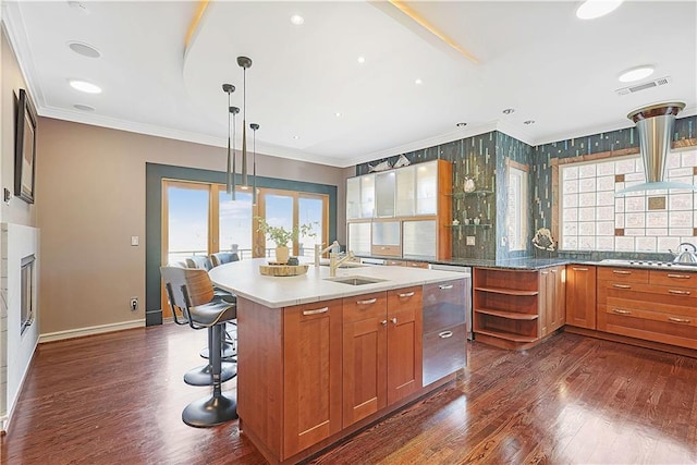 kitchen with decorative light fixtures, sink, an island with sink, and a wealth of natural light