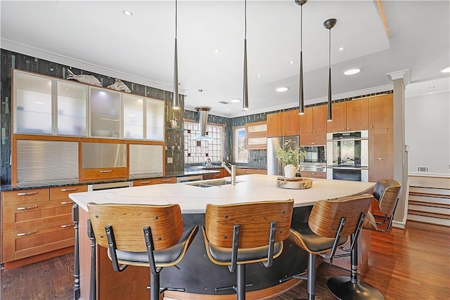 kitchen featuring appliances with stainless steel finishes, a kitchen island with sink, crown molding, sink, and pendant lighting