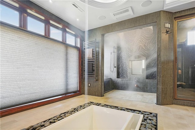 bathroom featuring tile patterned flooring, walk in shower, radiator, and tile walls