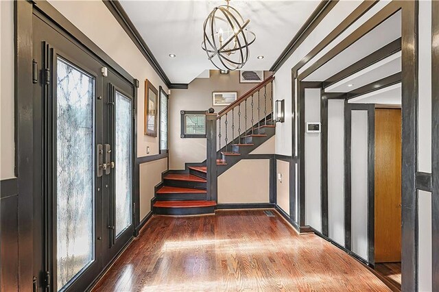 foyer featuring french doors, an inviting chandelier, a wealth of natural light, and crown molding