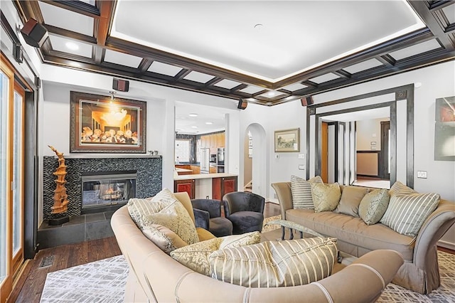 living room featuring beamed ceiling, dark hardwood / wood-style flooring, a fireplace, and coffered ceiling