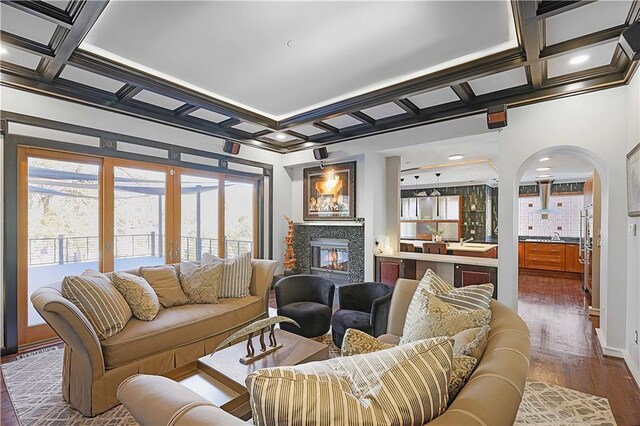 living room with coffered ceiling, crown molding, beamed ceiling, a fireplace, and dark hardwood / wood-style floors