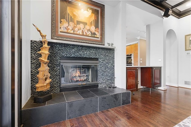 interior details with a tile fireplace, hardwood / wood-style floors, oven, and ornamental molding