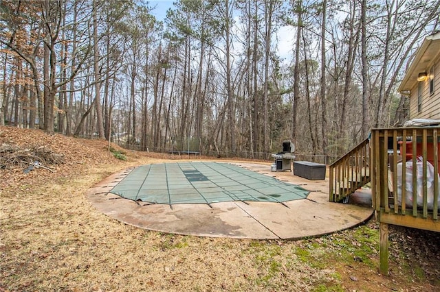 view of swimming pool featuring a trampoline, stairway, area for grilling, a patio area, and a covered pool