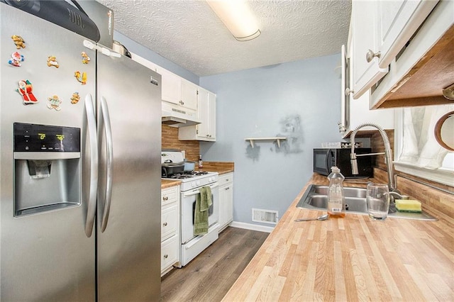 kitchen featuring stainless steel refrigerator with ice dispenser, visible vents, wooden counters, white range with gas cooktop, and under cabinet range hood