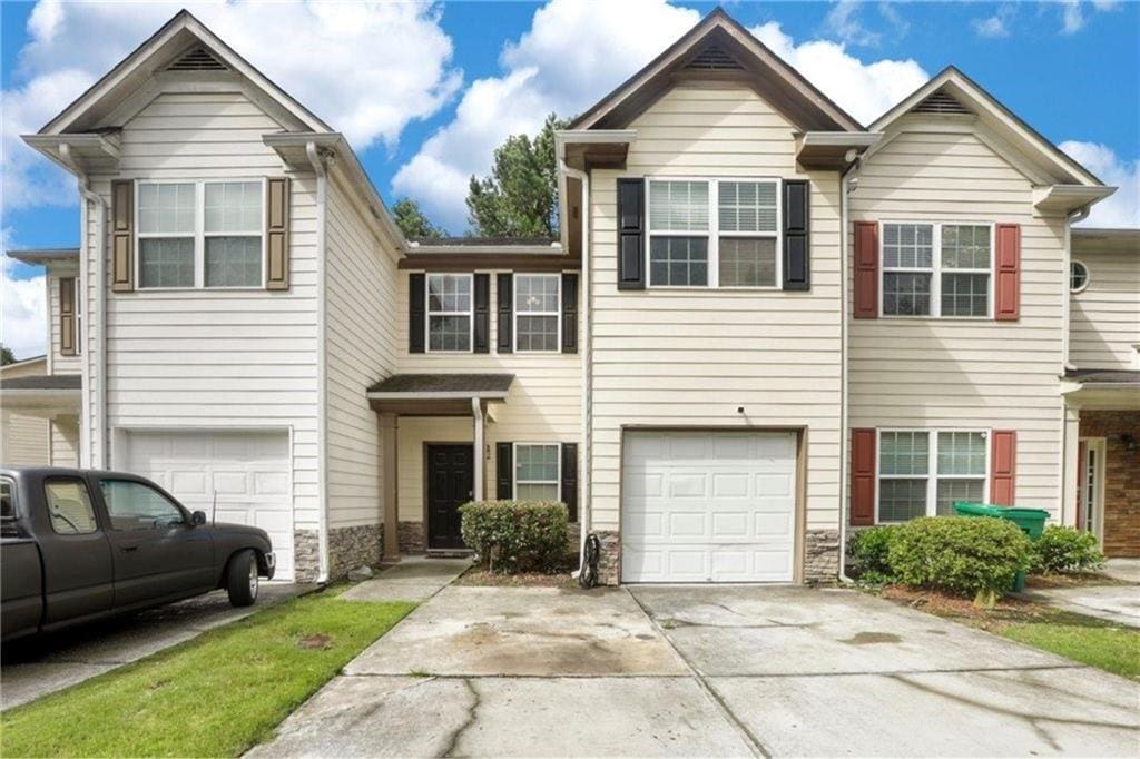 1540 Rogers Preserve Rd, Lithonia, GA 30058 - townhome / multi-family property featuring an attached garage, driveway, and stone siding