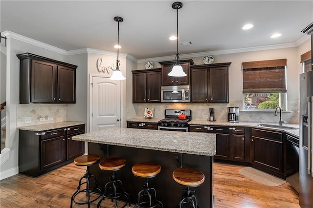 4305 Hunters Walk Way, Cumming, GA 30028 - kitchen featuring appliances with stainless steel finishes, a sink, dark brown cabinetry, a kitchen island, and ornamental molding