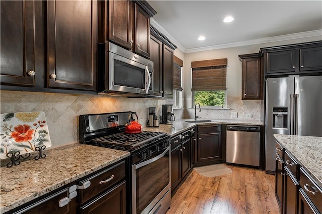 4305 Hunters Walk Way, Cumming, GA 30028 - kitchen featuring appliances with stainless steel finishes, a sink, light stone countertops, ornamental molding, and light wood-type flooring