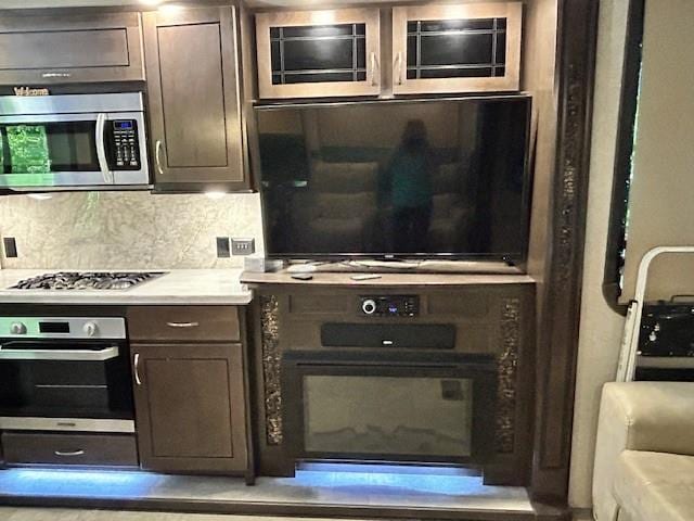 32 7th St, Ellijay, GA 30540 - kitchen with stainless steel appliances, dark brown cabinetry, decorative backsplash, light countertops, and glass insert cabinets