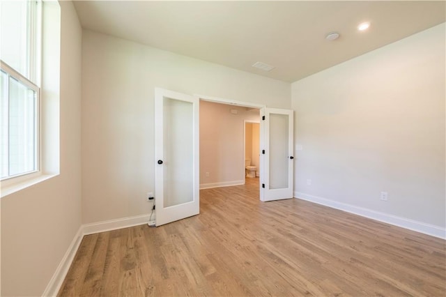 empty room with light wood-type flooring and french doors