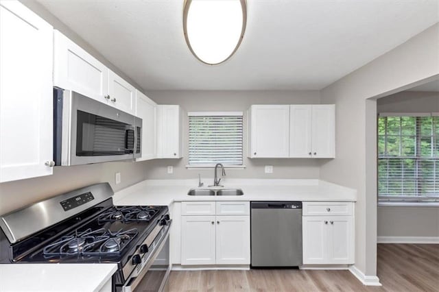5290 Forest Downs Ln, Atlanta, GA 30349 - kitchen featuring stainless steel appliances, a sink, light wood-type flooring, and white cabinets