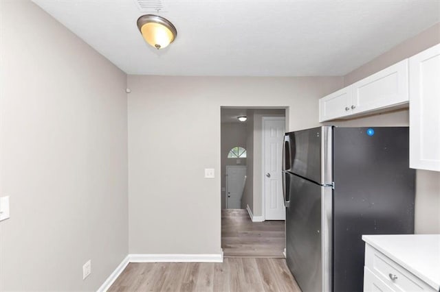 5290 Forest Downs Ln, Atlanta, GA 30349 - kitchen featuring freestanding refrigerator, white cabinets, light wood-style floors, light countertops, and baseboards