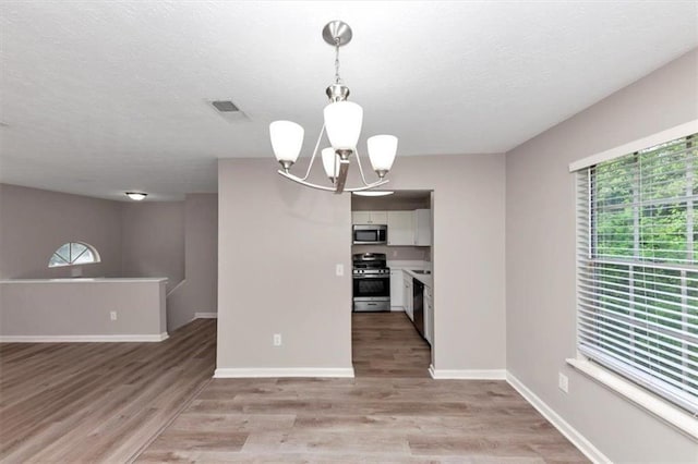 5290 Forest Downs Ln, Atlanta, GA 30349 - unfurnished dining area with a chandelier, light wood-style floors, baseboards, and a textured ceiling