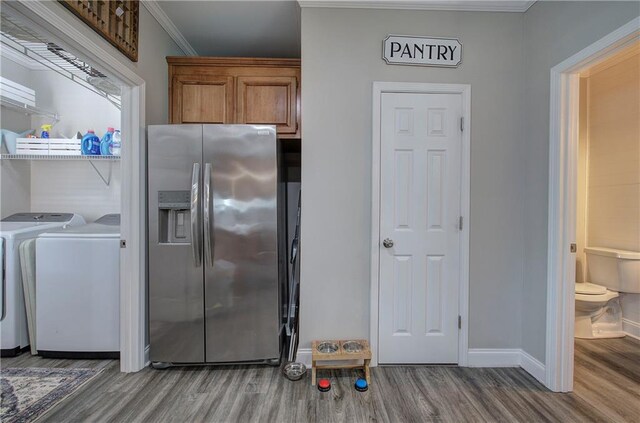 kitchen featuring ornamental molding, stainless steel fridge, washing machine and clothes dryer, and wood-type flooring