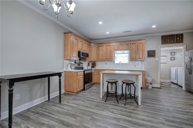 kitchen with light hardwood / wood-style flooring, independent washer and dryer, stainless steel appliances, and crown molding