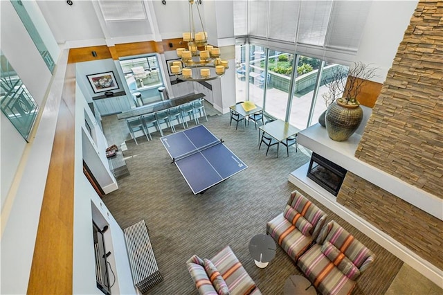 carpeted living room featuring a stone fireplace and a high ceiling