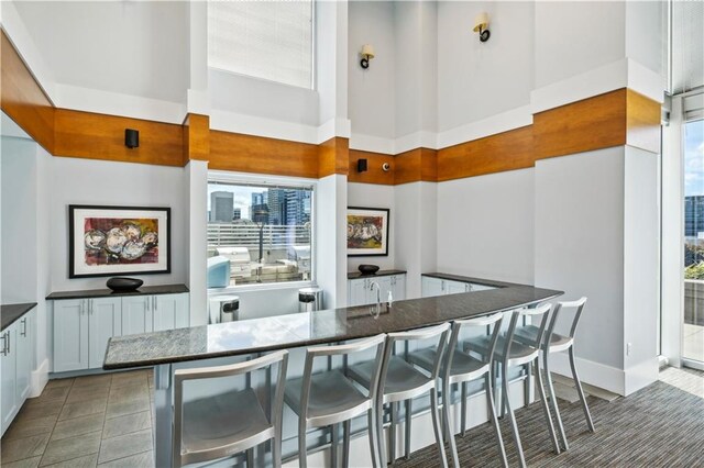 kitchen with white cabinets, a kitchen breakfast bar, and a towering ceiling