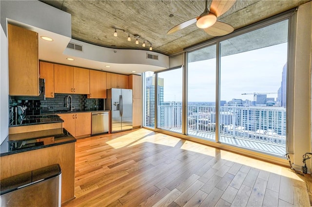 kitchen featuring decorative backsplash, stainless steel appliances, ceiling fan, sink, and light hardwood / wood-style flooring