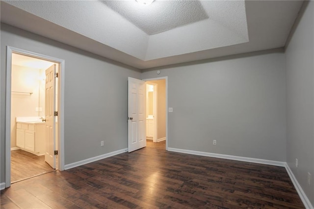 5069 Jonesboro Rd, Union City, GA 30291 - unfurnished bedroom featuring dark wood-type flooring, a tray ceiling, and connected bathroom