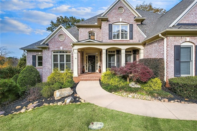 view of front facade featuring a shingled roof and brick siding