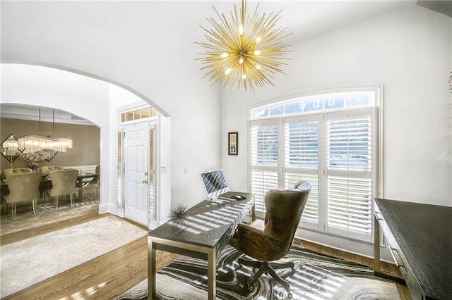 dining room featuring arched walkways, a notable chandelier, and wood finished floors