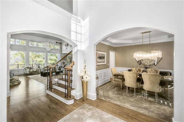 dining space featuring a wainscoted wall, a notable chandelier, ornamental molding, and wood finished floors