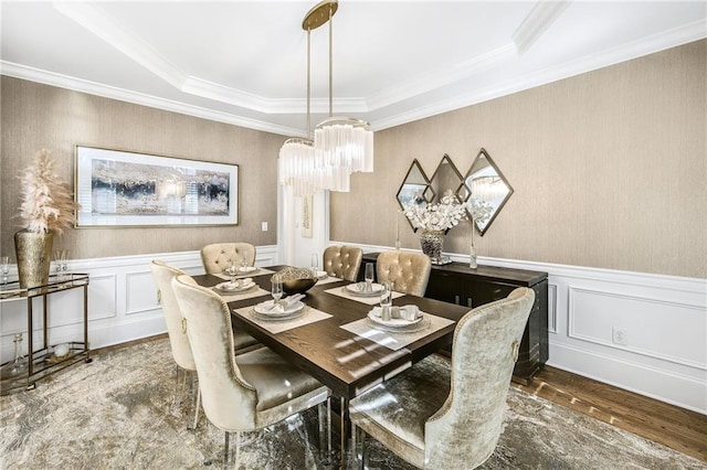 dining space with wainscoting, wood finished floors, and crown molding